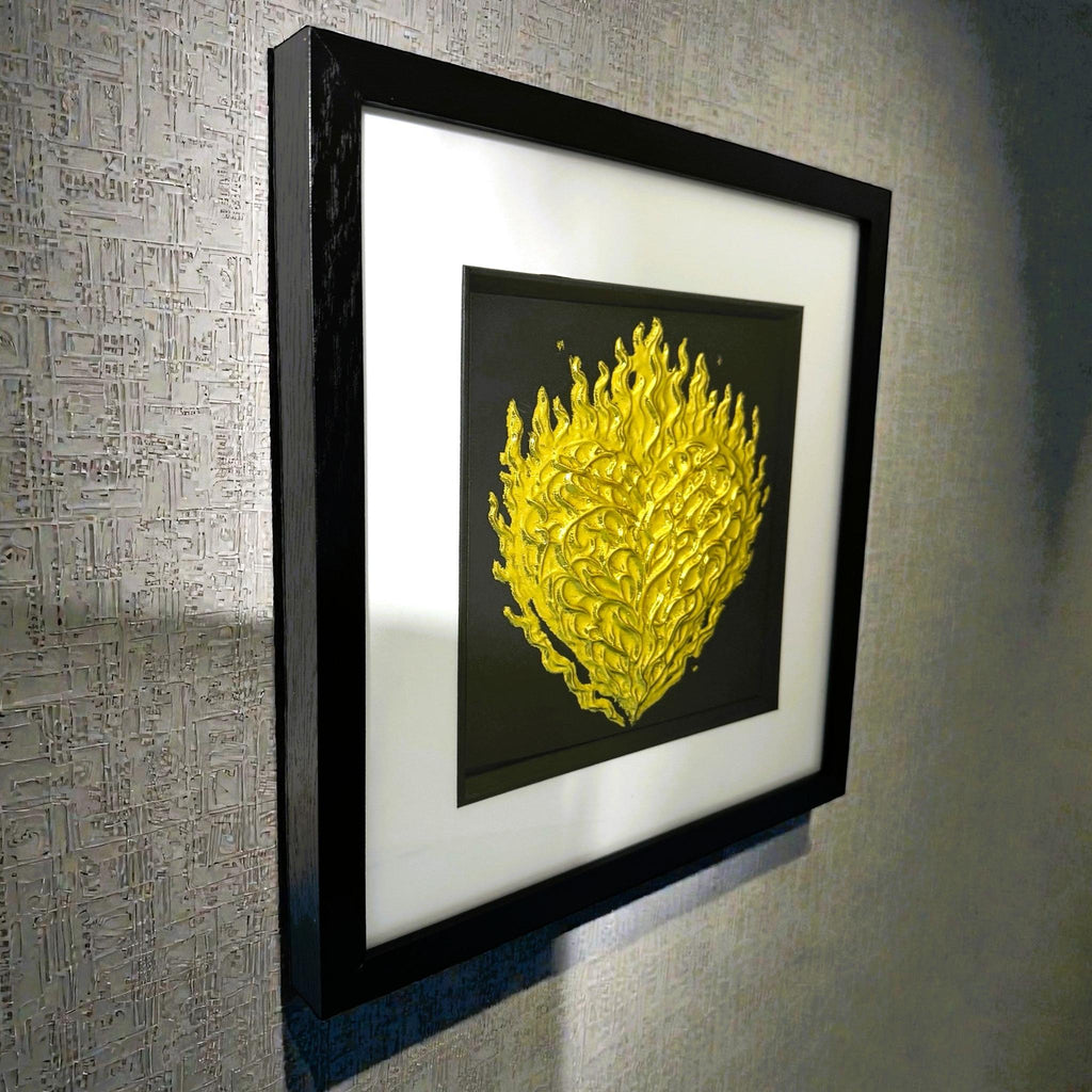 Angled wall-mounted view of flaming heart wall art framed in black with white mount