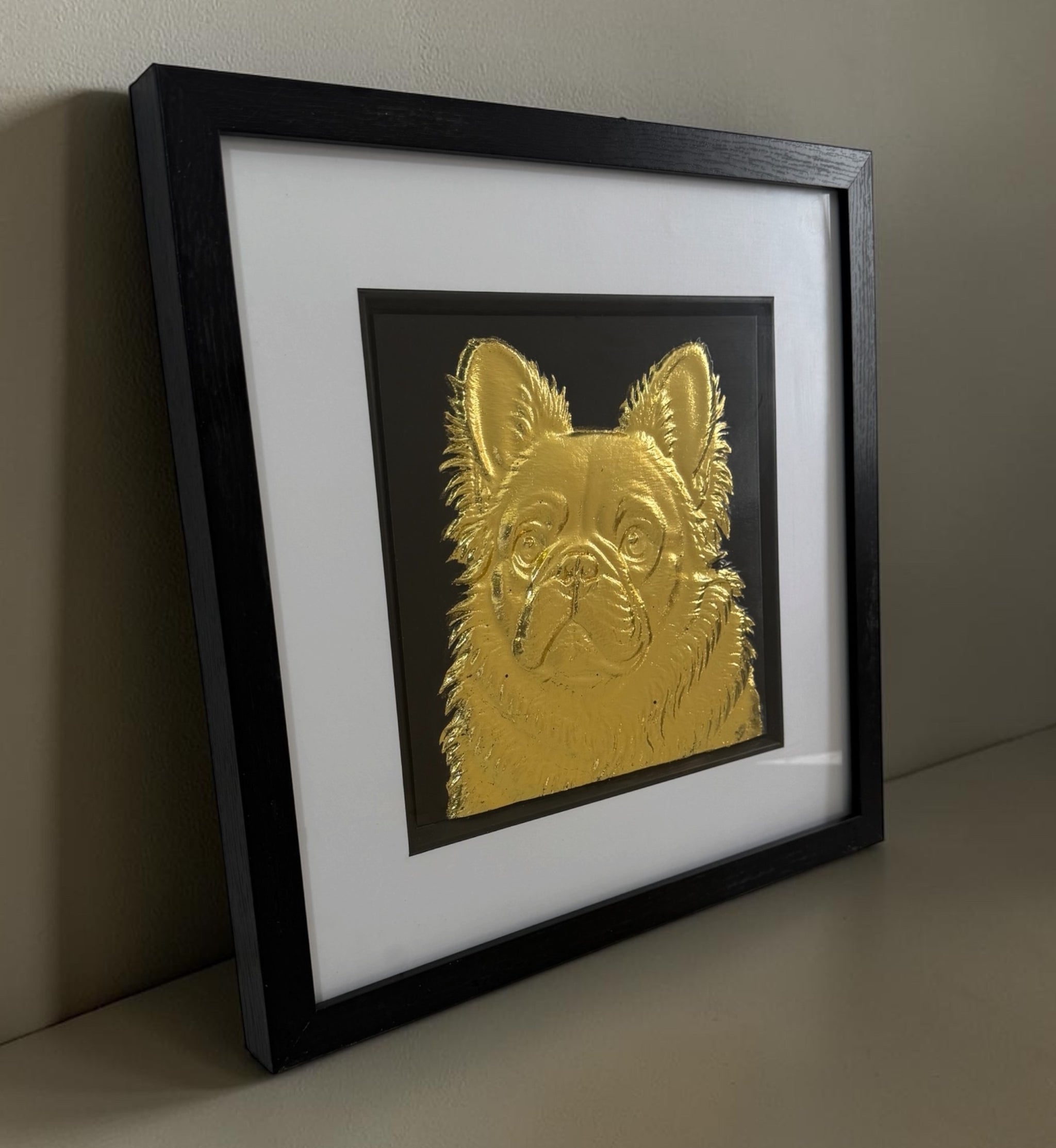 Angled gold fluffy Frenchie framed artwork showing raised relief detail through the glass front.