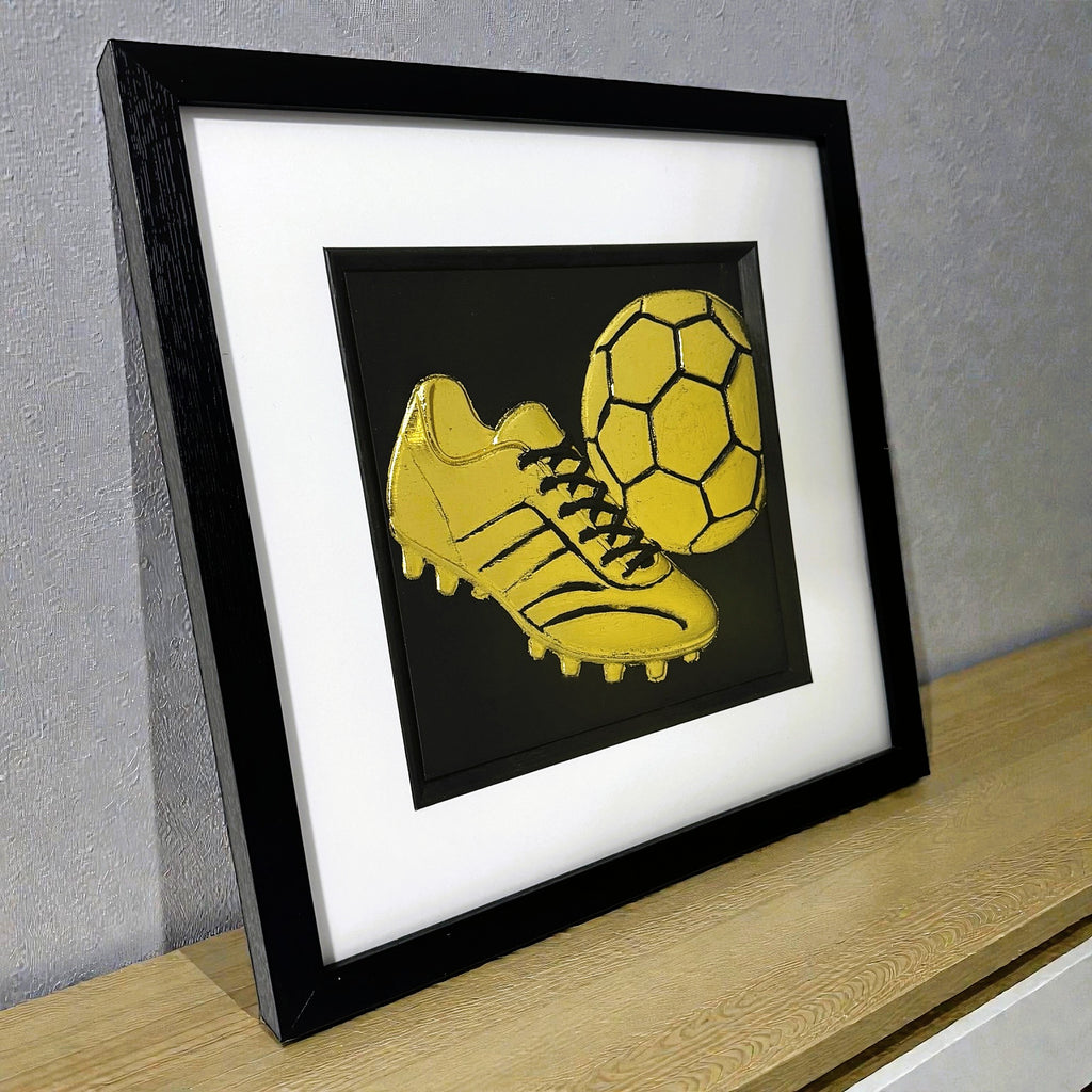 Framed gold football art displayed on shelf for bedroom decor.