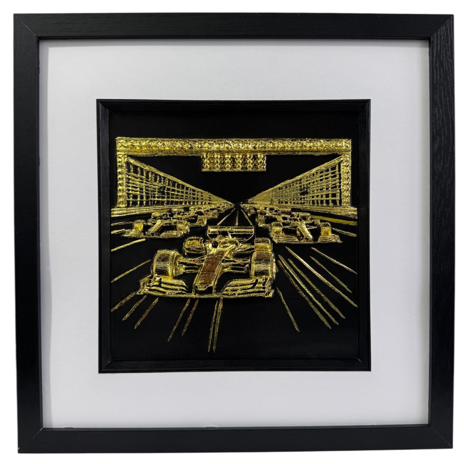 A luxury 3D relief sculpture of a Formula 1 starting grid featuring five race cars and start lights, finished in metallic gold leaf and framed in black.