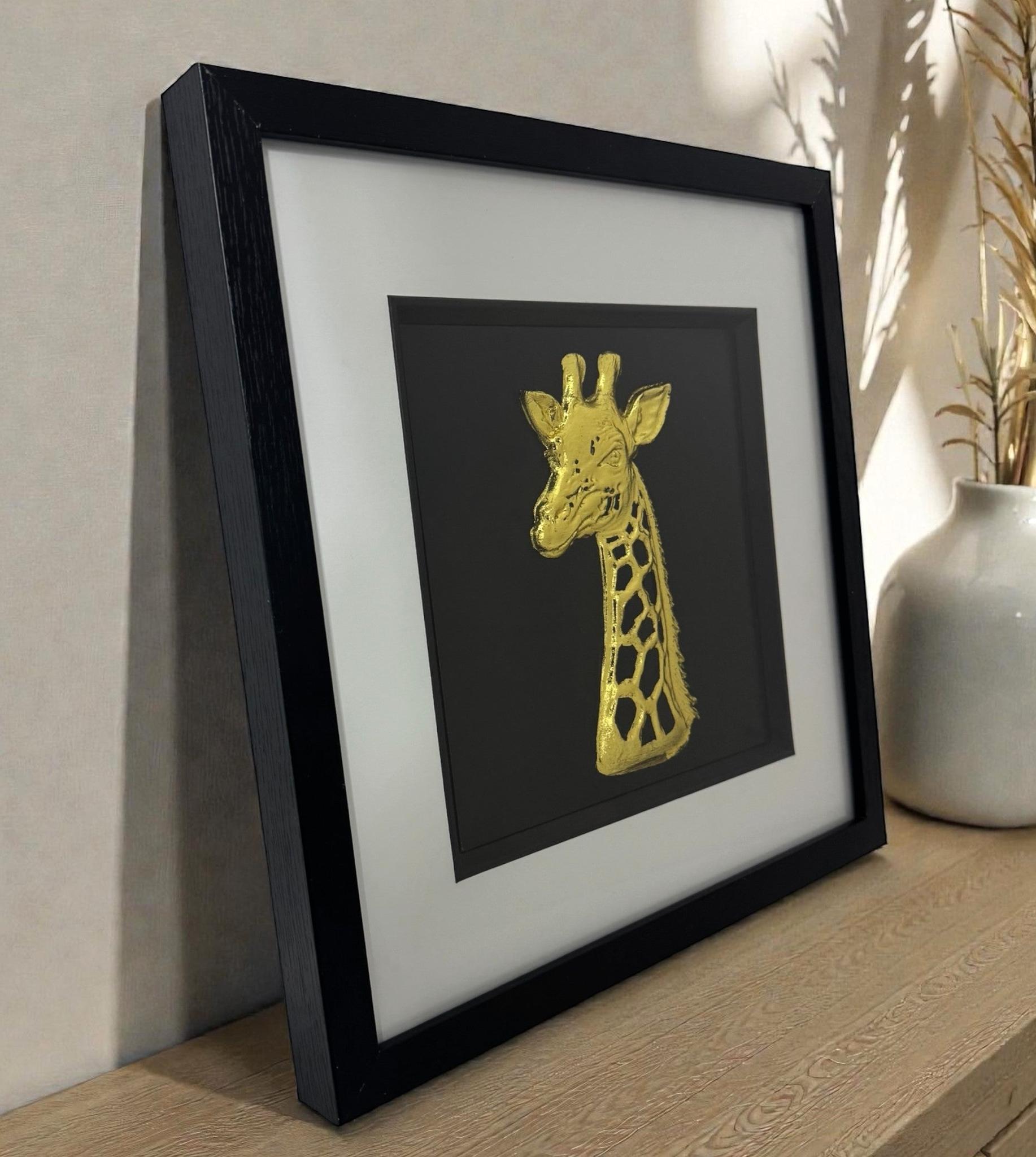 3D giraffe wall art gold leaf in a black box frame with white mount, modern giraffe wall decor styled on a sideboard.