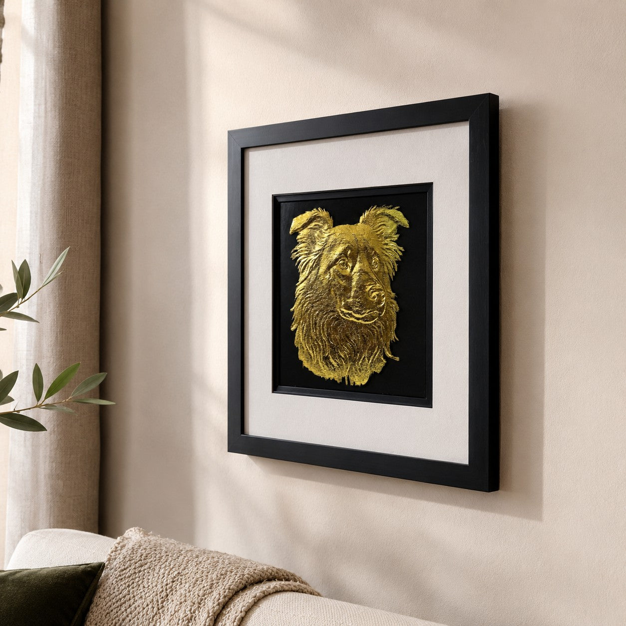 Angled lifestyle view of gold Border Collie framed wall art hung on a neutral wall beside soft furnishings, natural light and subtle greenery.