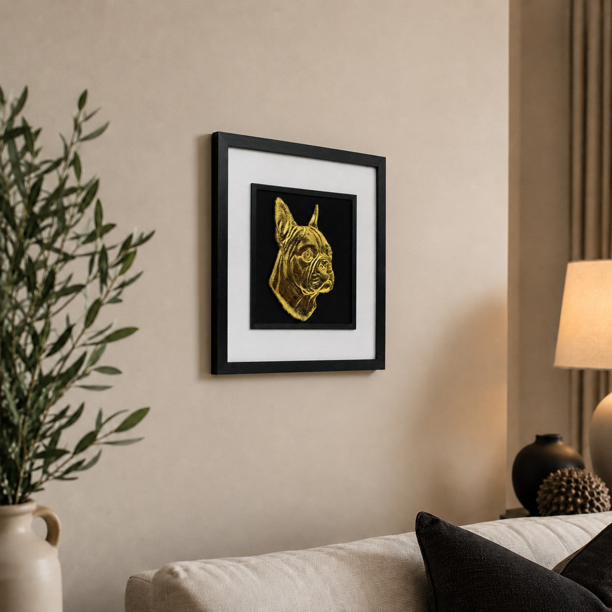 Angled lifestyle view of gold Boston Terrier framed wall art hung on a neutral wall above a cosy sofa with soft lighting, greenery and elegant black accents.