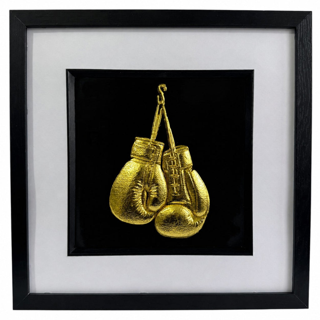 Framed gold boxing gloves wall art with black frame, white mount and black background, featuring detailed gold leaf style boxing glove design for sports decor or boxing gift.