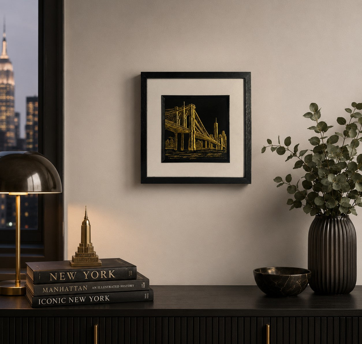 Gold Brooklyn Bridge New York wall art displayed in a modern urban interior, featuring a framed hand gilded gold leaf 3D relief bridge and skyline design on a black background.