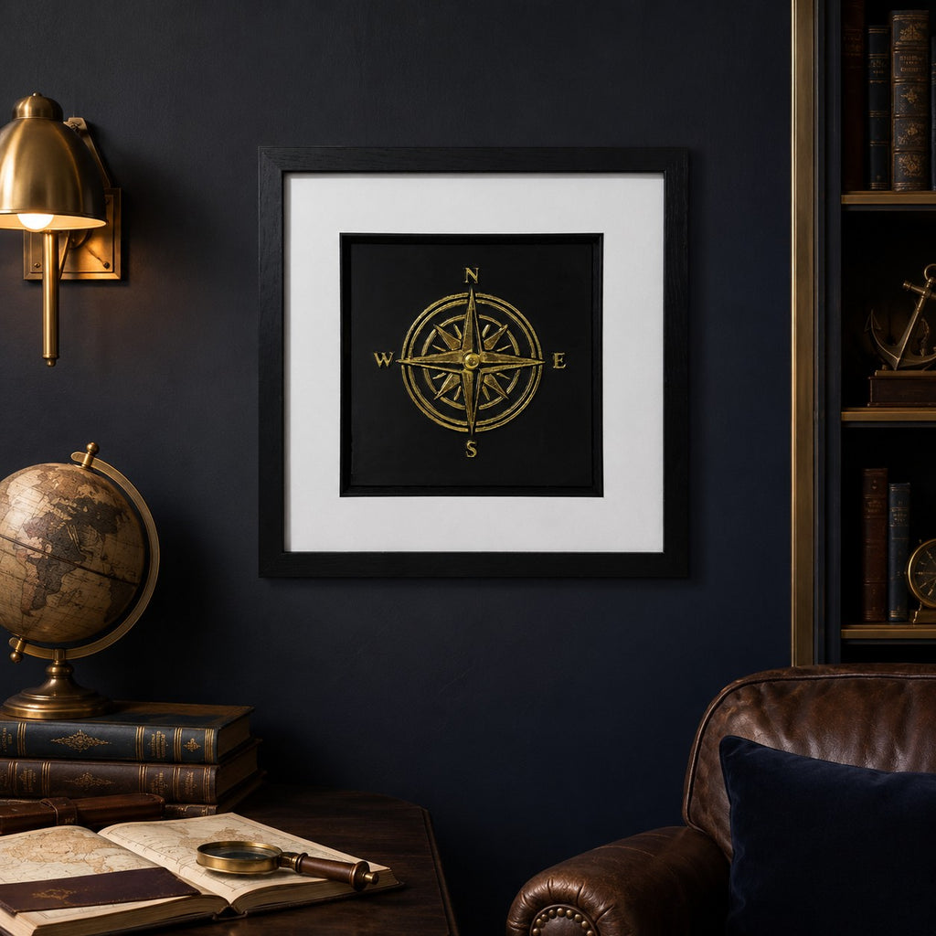 Gold compass framed wall art displayed on a dark study wall with nautical decor, antique globe, leather chair, warm brass lighting and explorer-inspired accents.