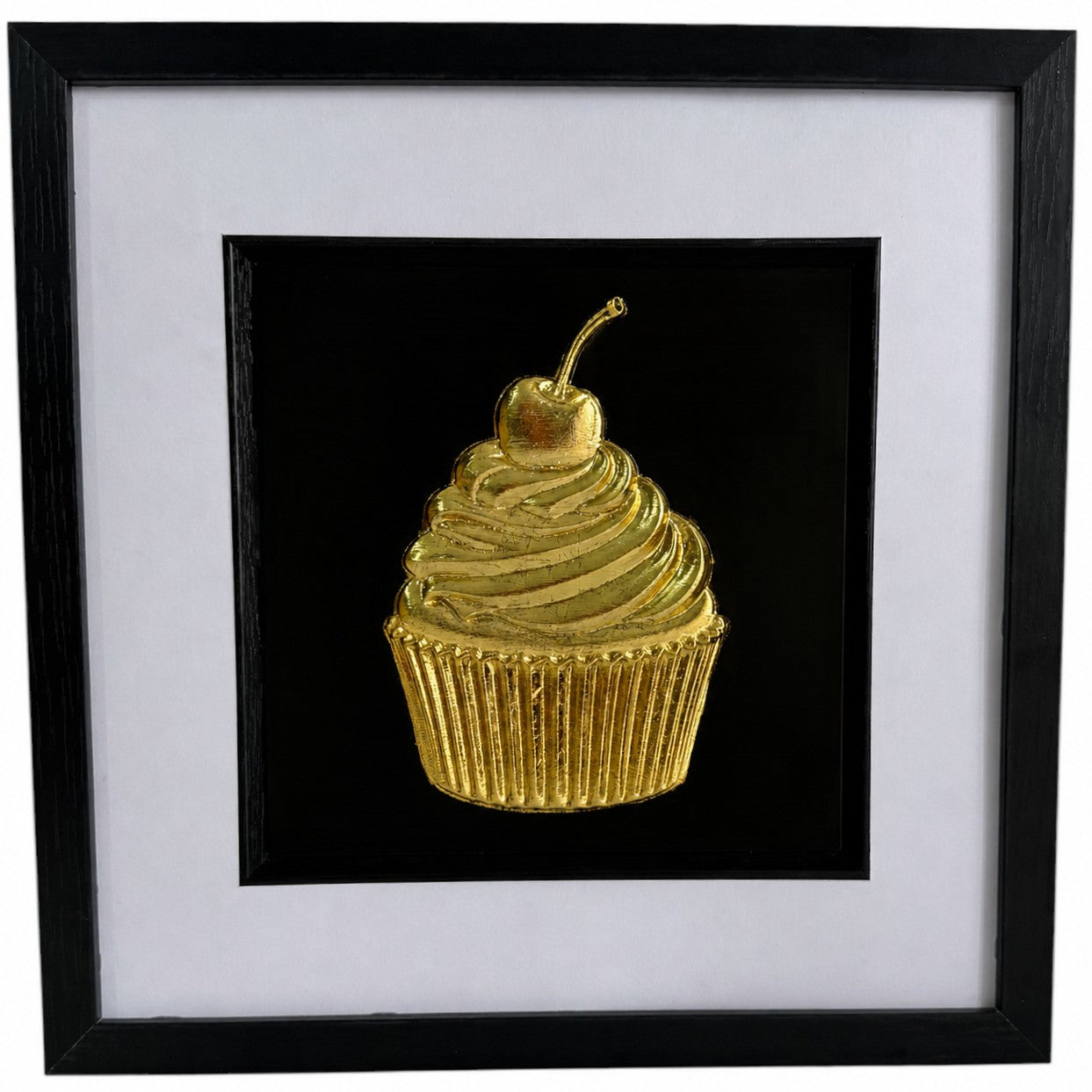 Gold cupcake relief artwork with cherry in a black square frame with white mount.