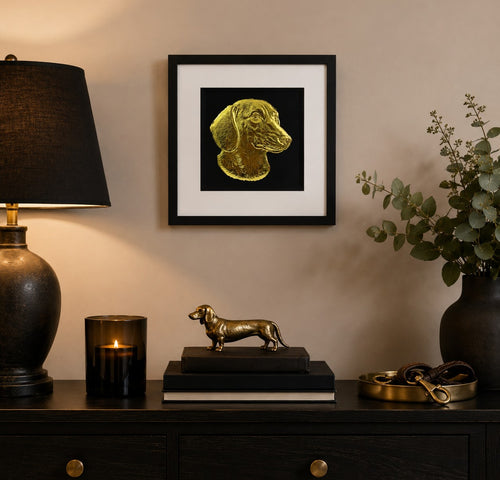 Framed gold Dachshund sausage dog wall art on a black background, styled in a warm modern dog lover home interior with black, gold and neutral decor accents.