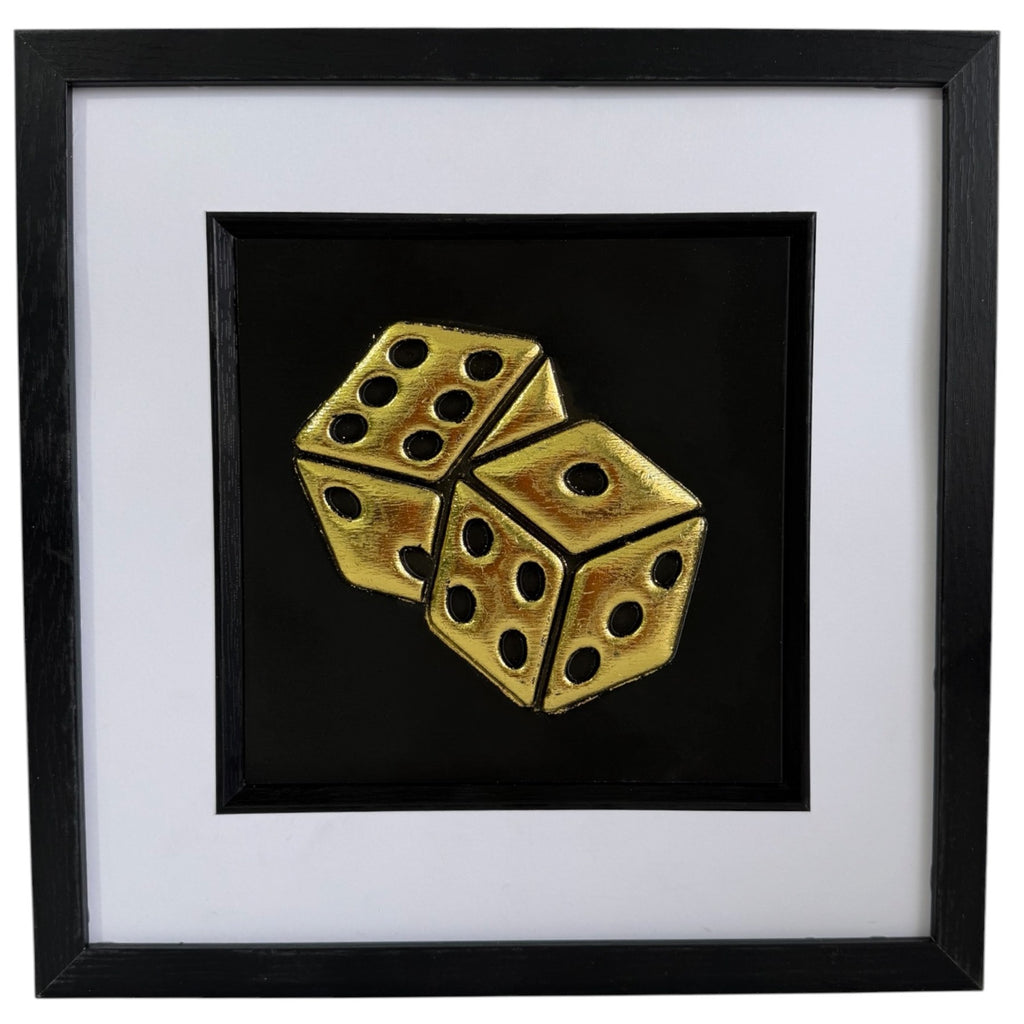 Framed gold leaf dice wall art with two raised dice on a black background, finished with a white mount and black frame.
