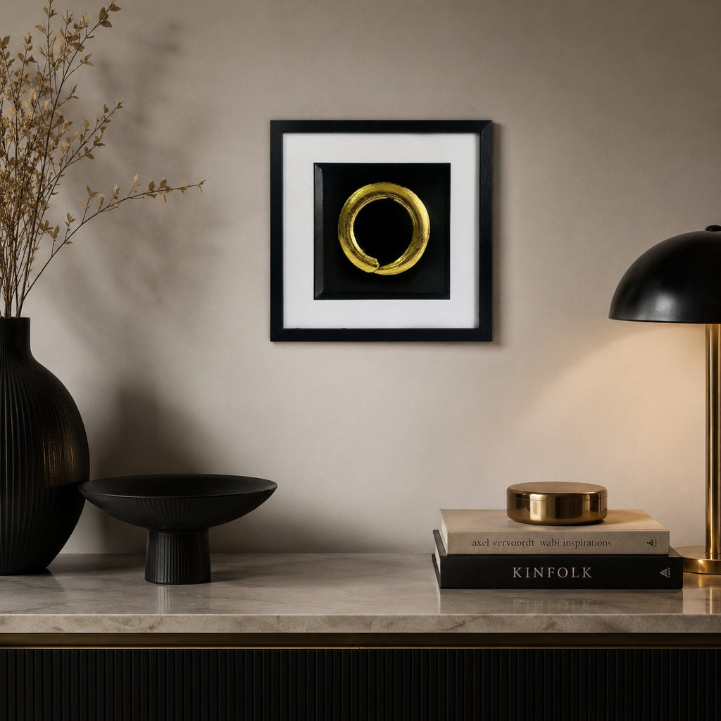 Gold enso circle wall art displayed in a calm Japandi inspired interior, featuring a 33 cm square framed hand gilded gold leaf 3D relief design on a black background with minimalist neutral decor.