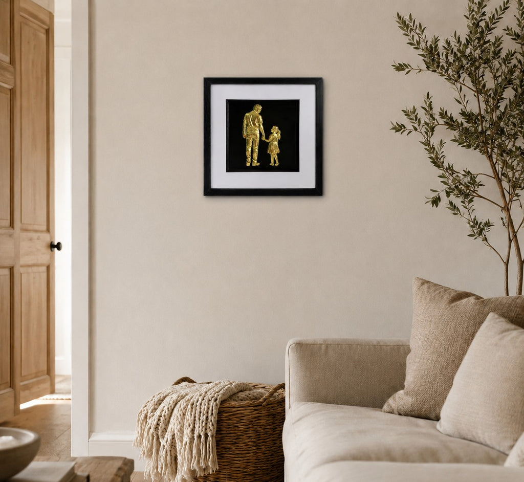 Gold father and daughter framed wall art on a warm neutral living room wall, shown as a sentimental family gift with black frame and white mount.