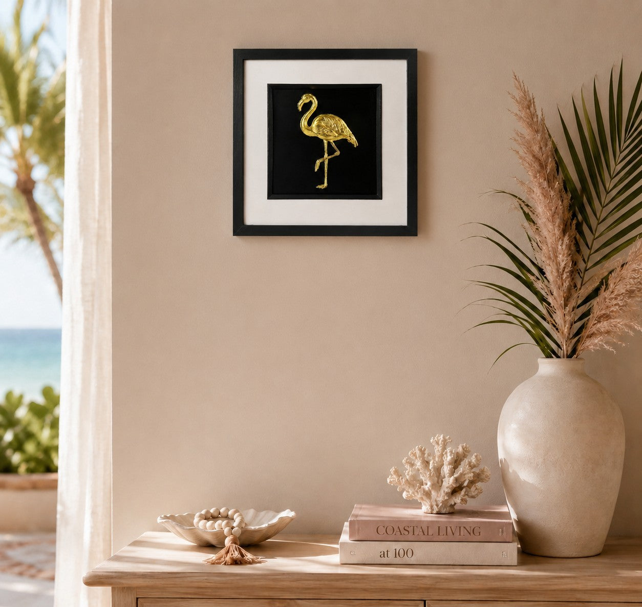 Gold flamingo wall art displayed in a tropical coastal interior, featuring a 33 cm square framed hand gilded gold leaf 3D relief flamingo design on a black background.