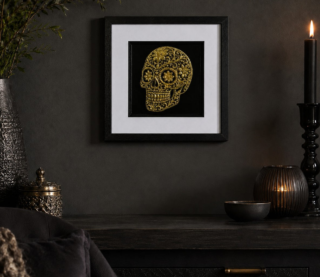 Gold floral sugar skull framed artwork in a dark gothic lifestyle scene with candlelight and black accessories