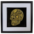 Gold floral sugar skull relief in a black frame with glass front, white mount and black inner surround
