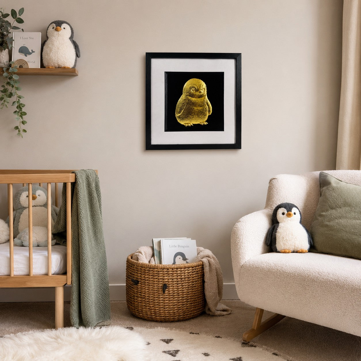 Framed gold leaf baby penguin wall art displayed in a soft neutral nursery with a cot, rocking chair, woven basket and penguin toys.