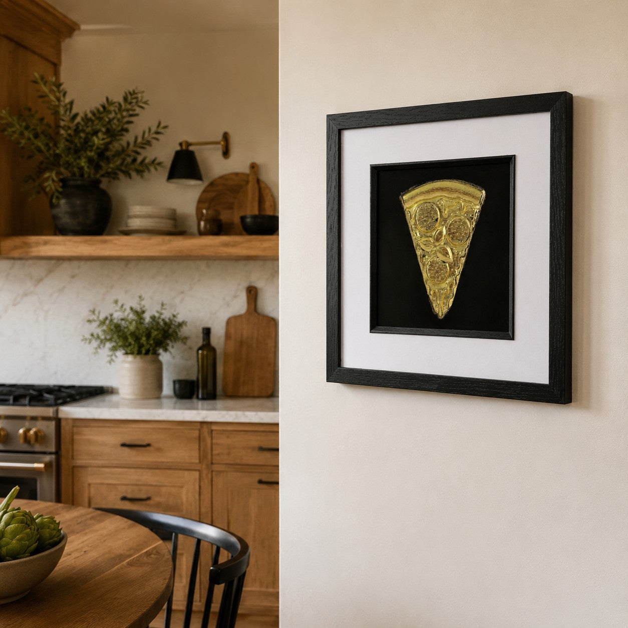 Gold pizza slice framed artwork styled on a modern kitchen wall with wood cabinetry and neutral tones.