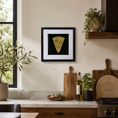 Gold 3D pizza slice artwork in black frame styled on a kitchen wall with wood boards, herbs and neutral decor.