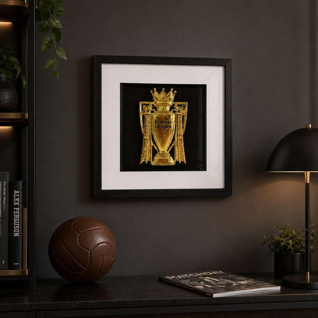 Gold Premier League trophy framed artwork styled in a dark football room with lamp, football, books and plant detail