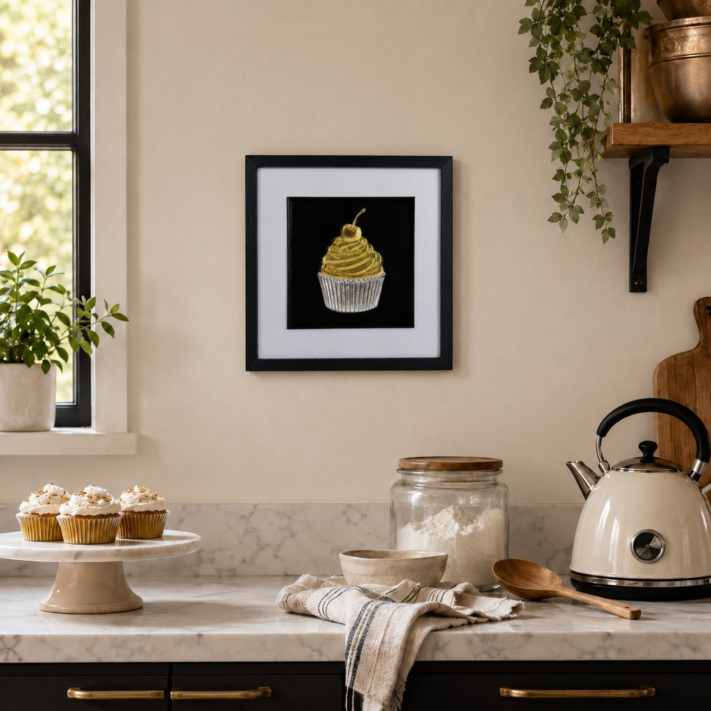 Gold and silver cupcake artwork styled on a kitchen wall above a marble-style worktop with baking accessories.