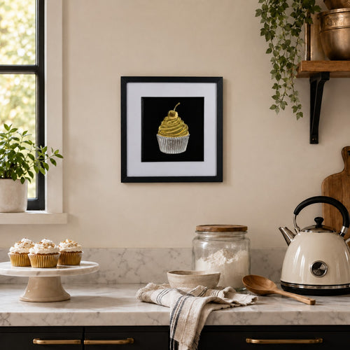 Gold and silver cupcake artwork styled on a kitchen wall above a marble-style worktop with baking accessories.