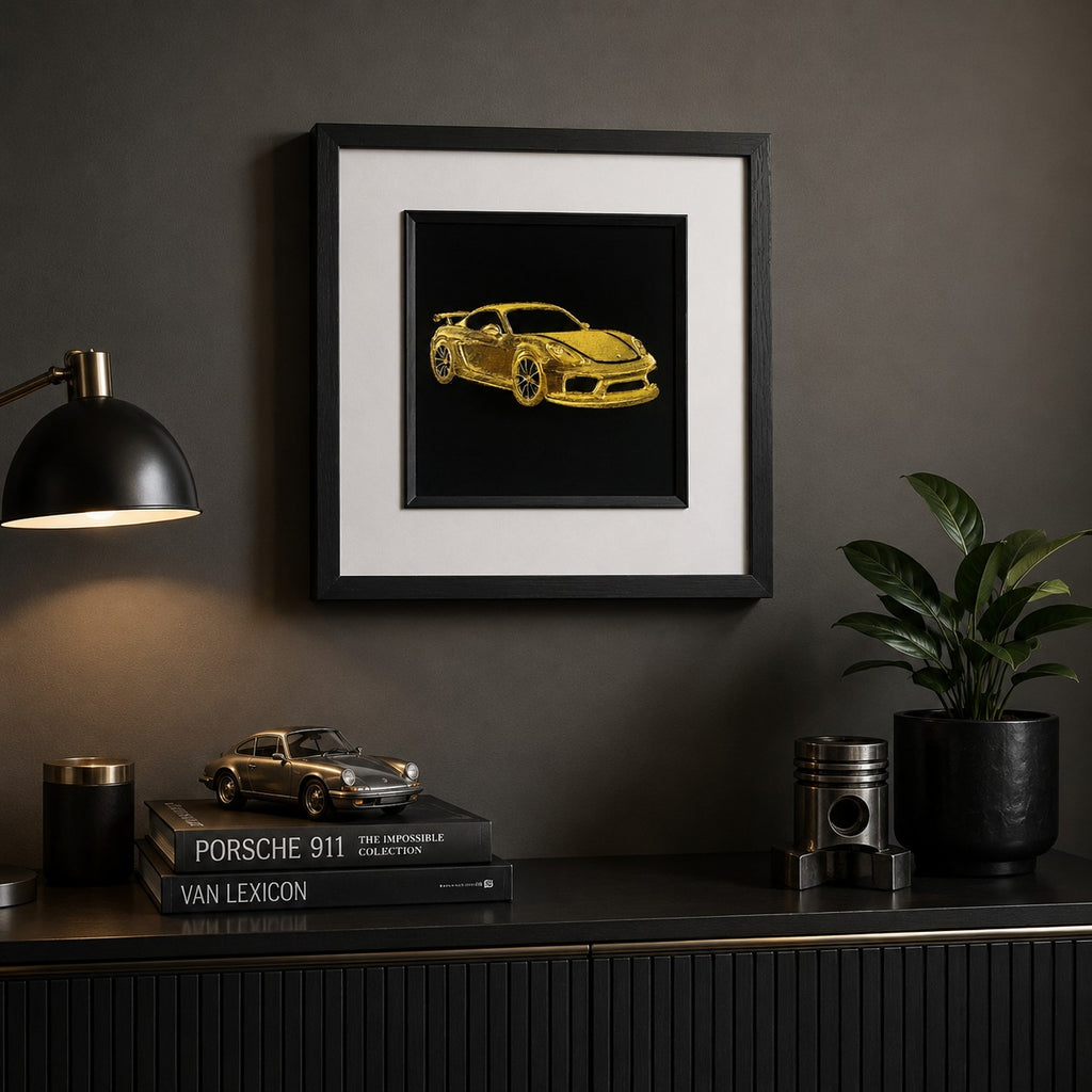 Gold sports car wall art displayed in a modern automotive inspired room, featuring a framed hand gilded gold leaf 3D relief car design on a black background with luxury masculine decor.