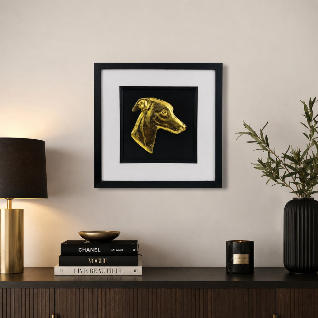 Gold whippet dog portrait wall art in a black frame with white mount, styled on a neutral wall above a dark wooden sideboard with luxury home decor.