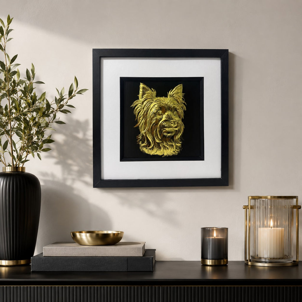 Gold Yorkshire Terrier wall art in a black frame with white mount, styled on a neutral wall above a dark console table with elegant gold and black home decor accents.