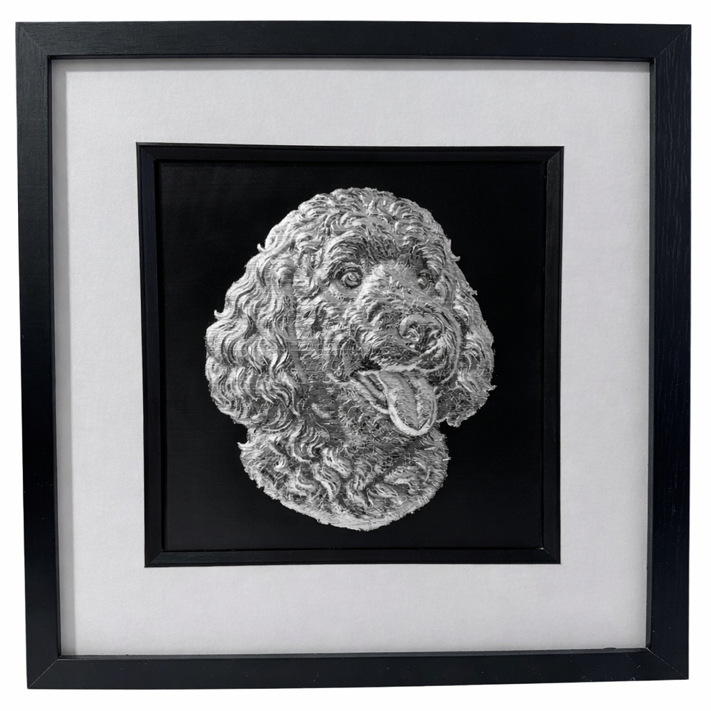 Goldendoodle framed wall art showing a sculpted dog portrait with curly coat in silver leaf, set on a black background with white mount and black wooden frame
