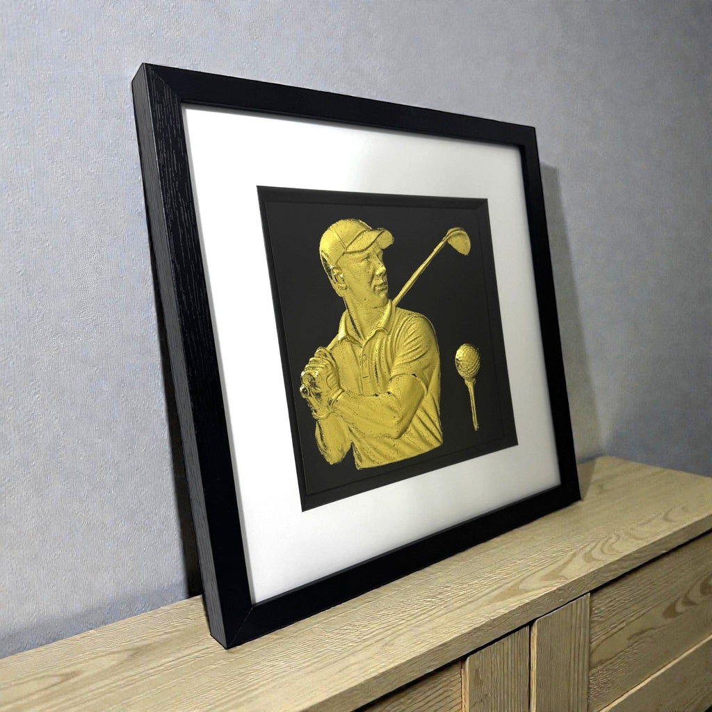 Framed gold golfer 3D art displayed on wooden shelf.