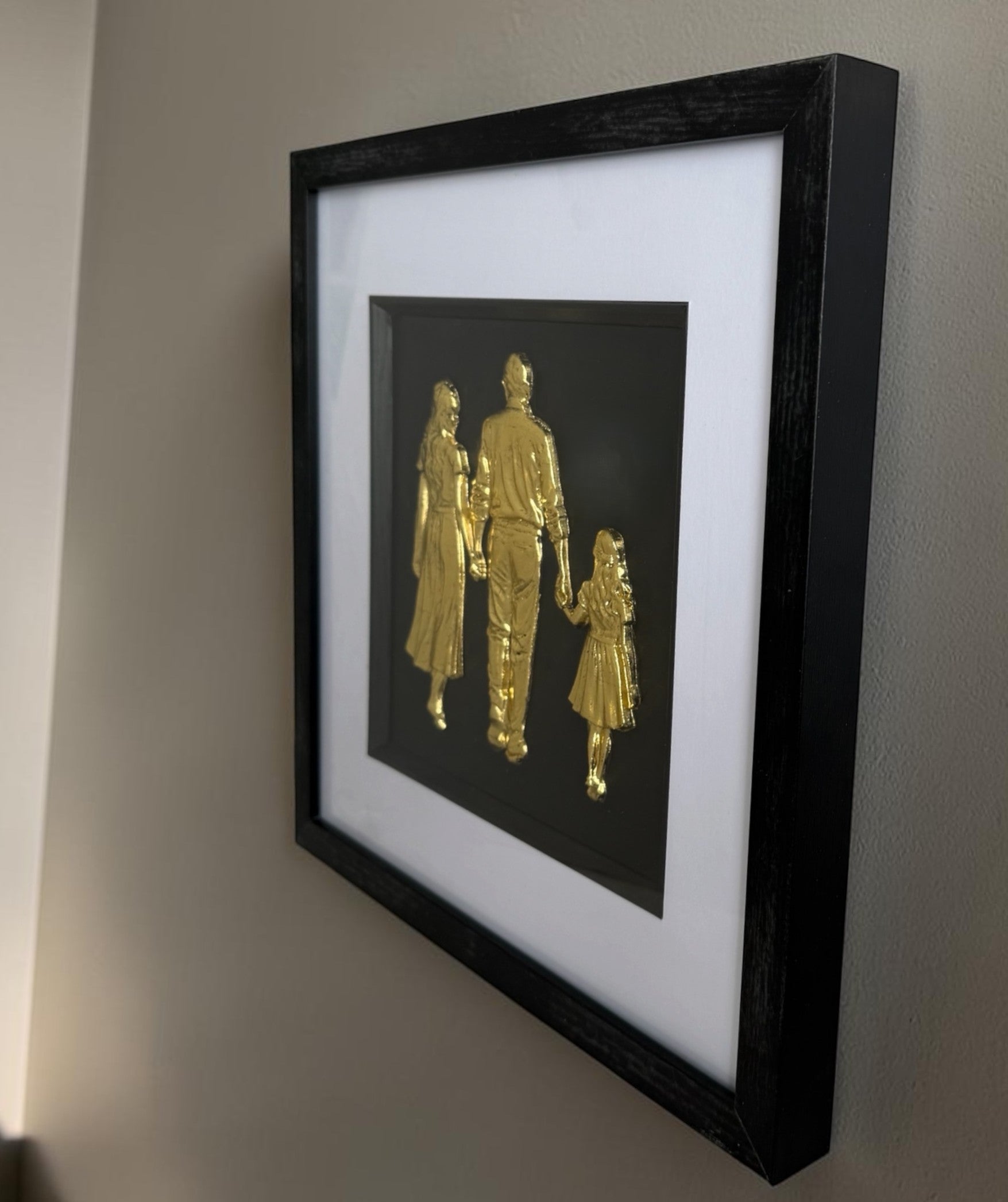Side view of Gold raised family artwork showing frame depth, black box frame and white mount.