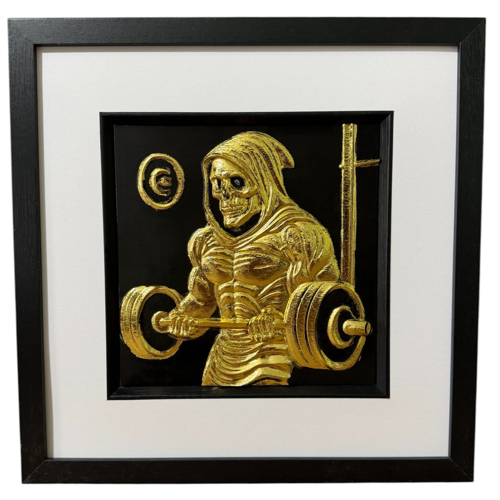 Framed grim reaper gym wall art, gold relief of a hooded skeleton lifting a loaded barbell, scythe propped behind him, on a black background in a black frame with white mount