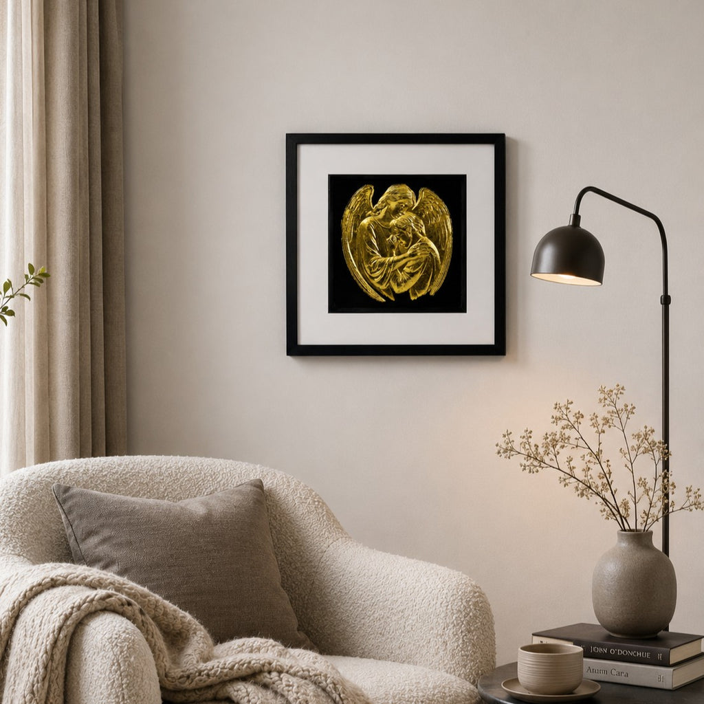 Gold leaf guardian angel wall art in a black frame displayed in a calm neutral living room above a textured armchair.