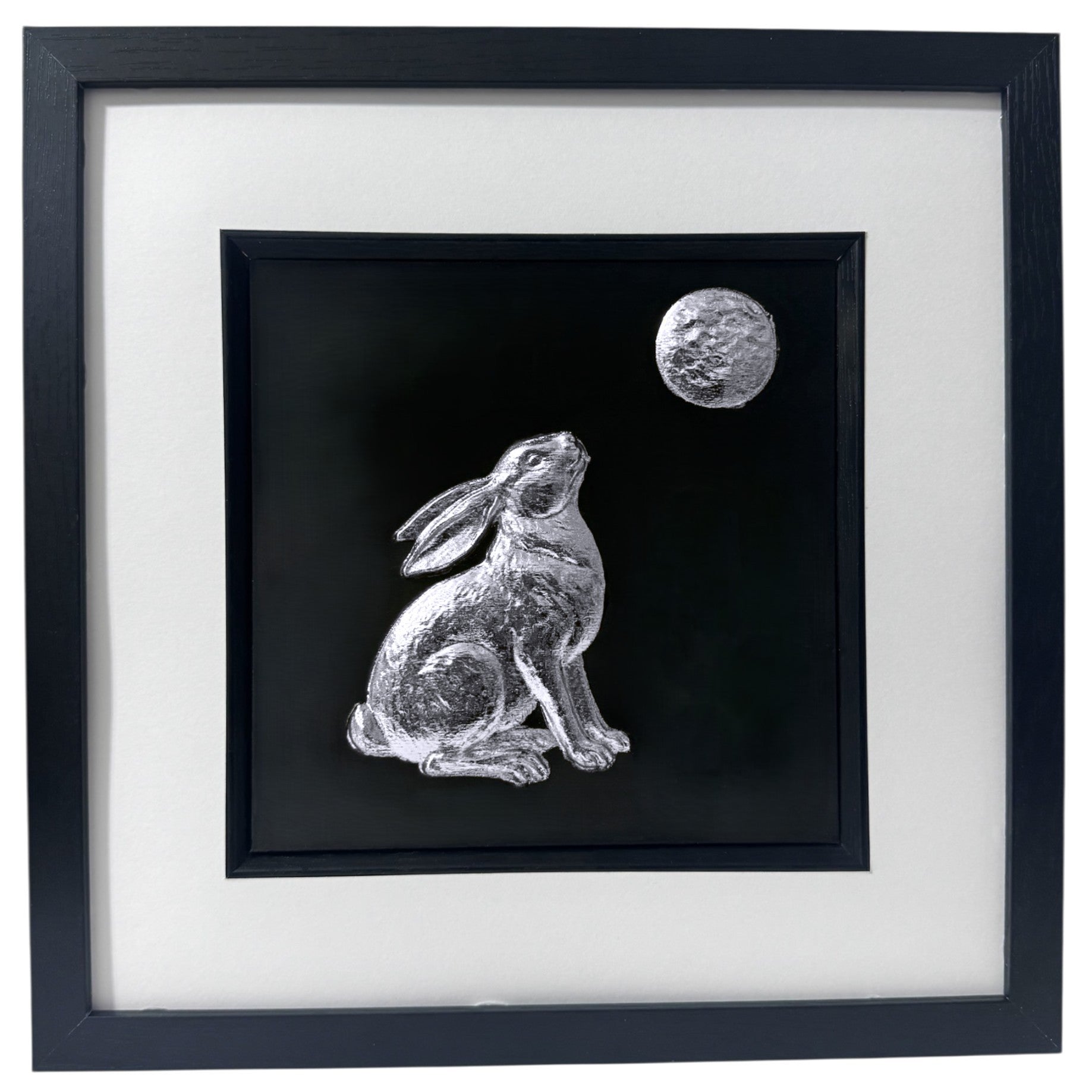 A handmade silver leaf Moon Gazing Hare wall art piece, capturing the celestial glow of the moon against a black background.