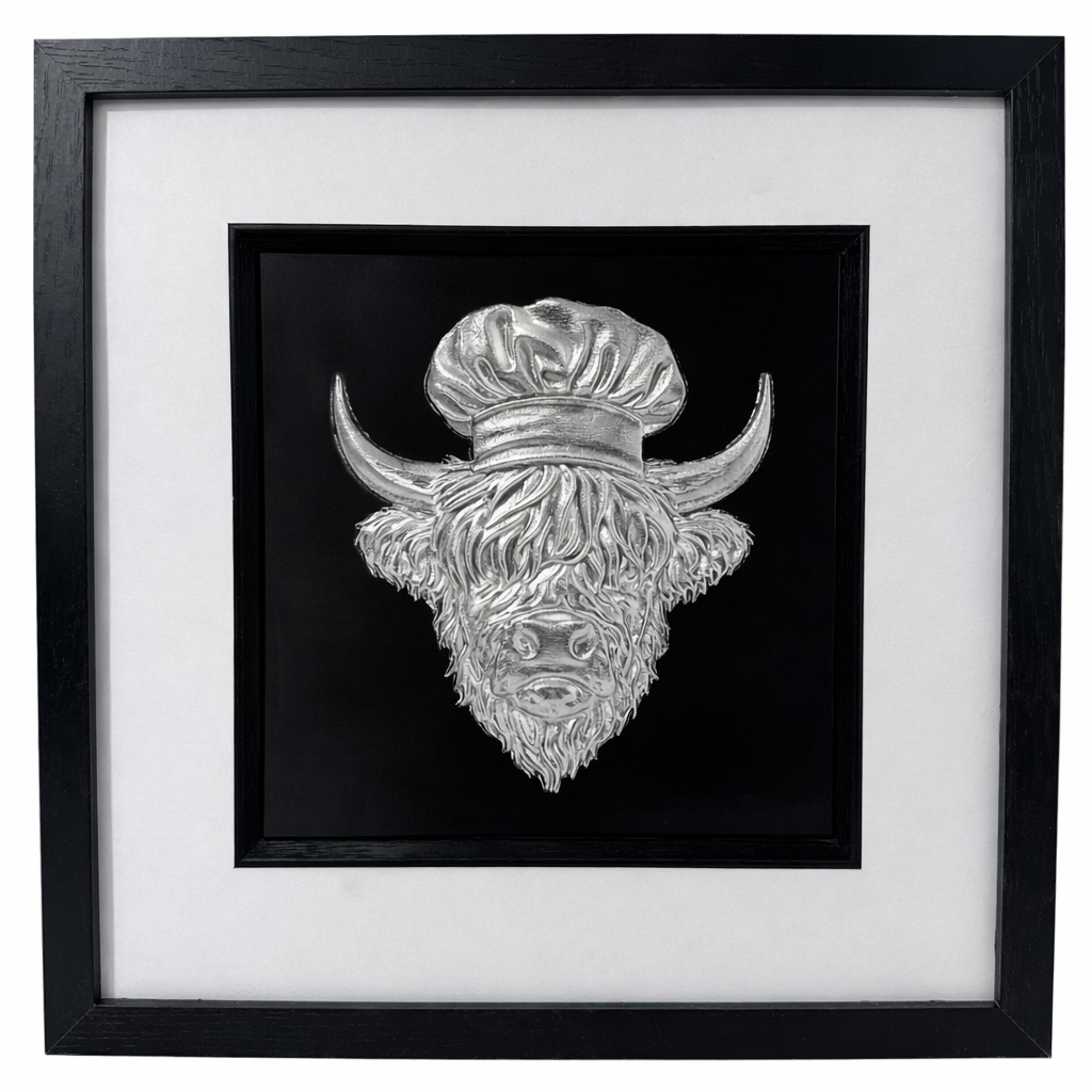 Silver Highland cow chef relief in a black box frame with wide white mount and black inner surround.