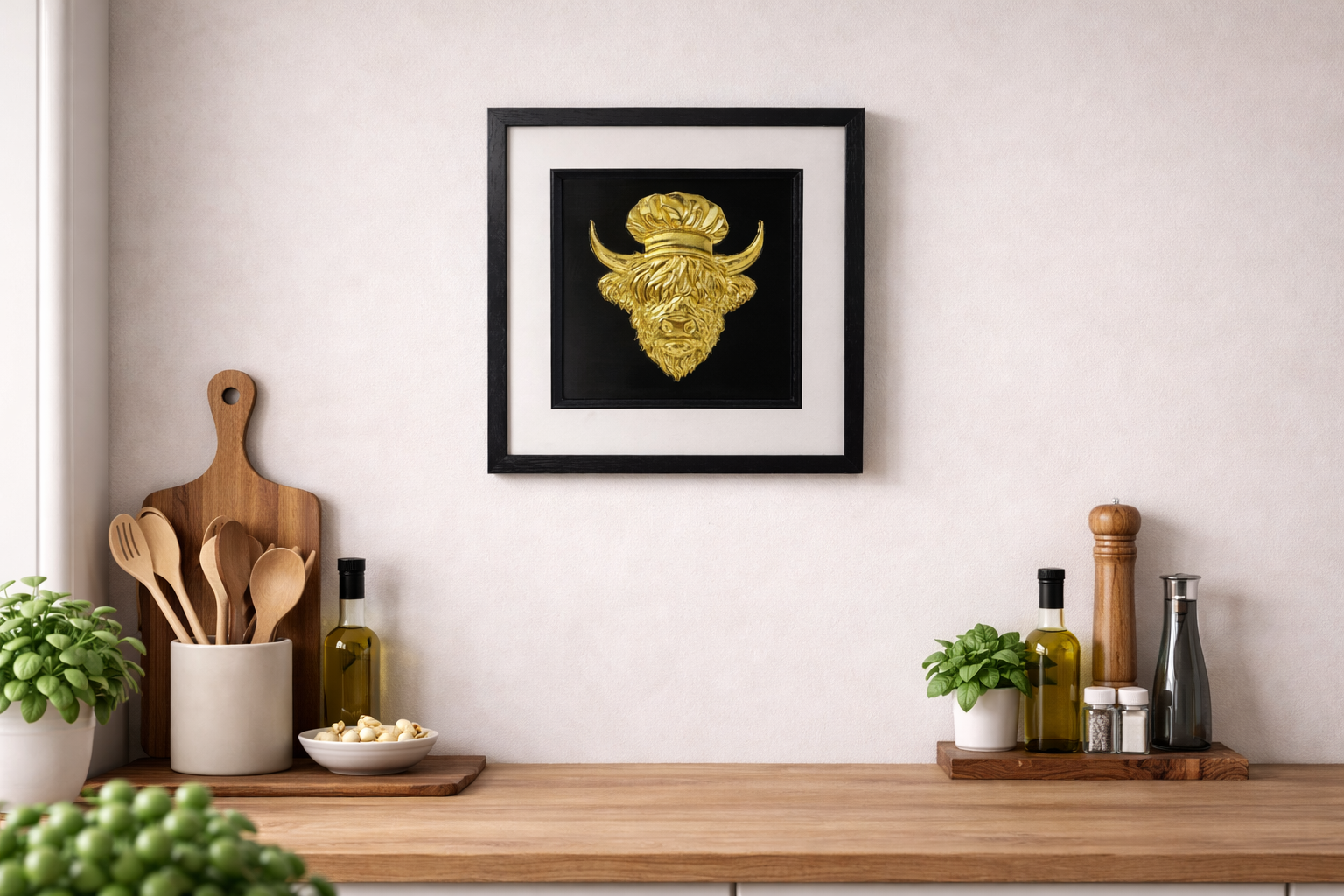 Framed 3D Highland cow chef wall art in gold, styled above a wooden kitchen counter with utensils, herbs, and olive oil bottles.