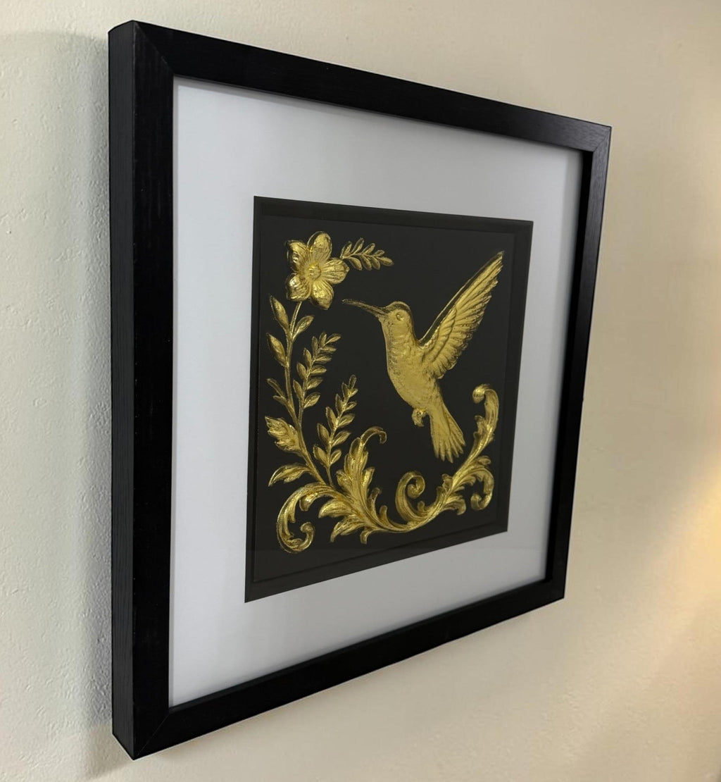 Close angled view of Gold 3D hummingbird and flower artwork with raised wing and botanical leaf detail