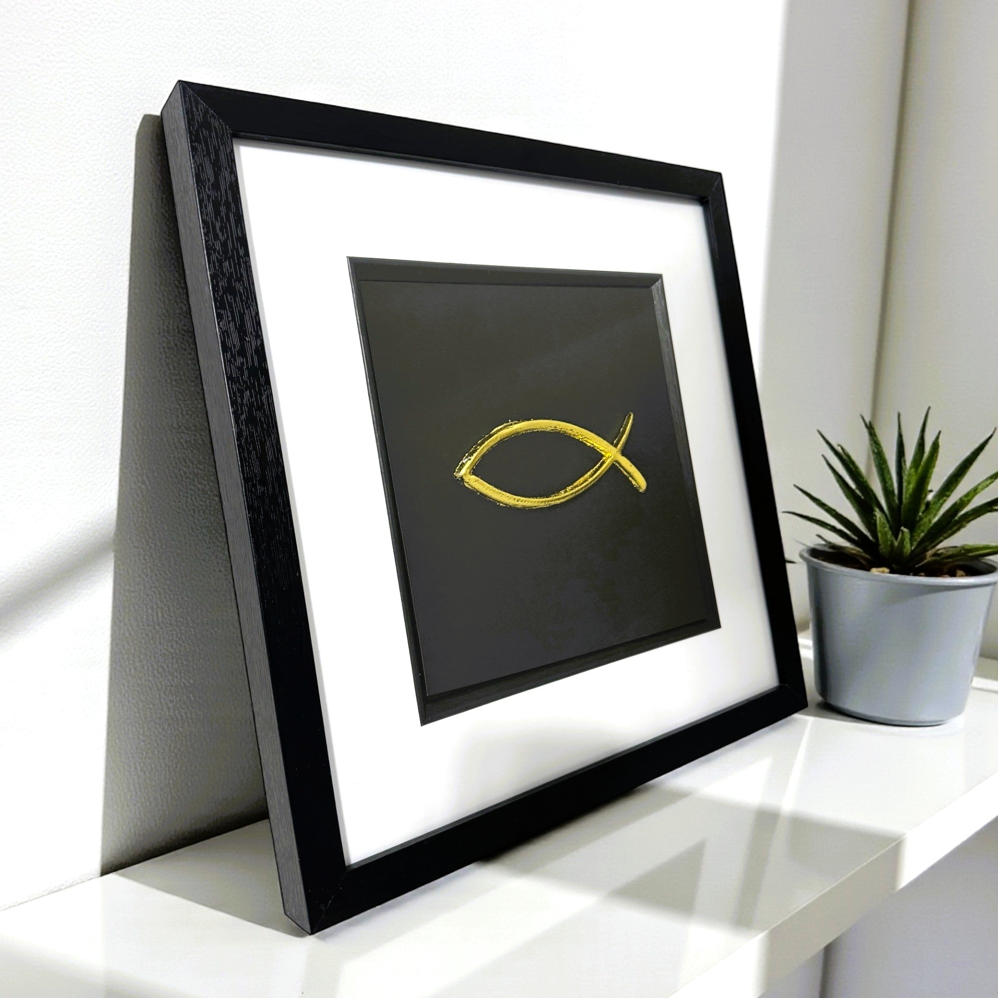 Gold leaf Ichthys fish symbol relief on black background on a desk