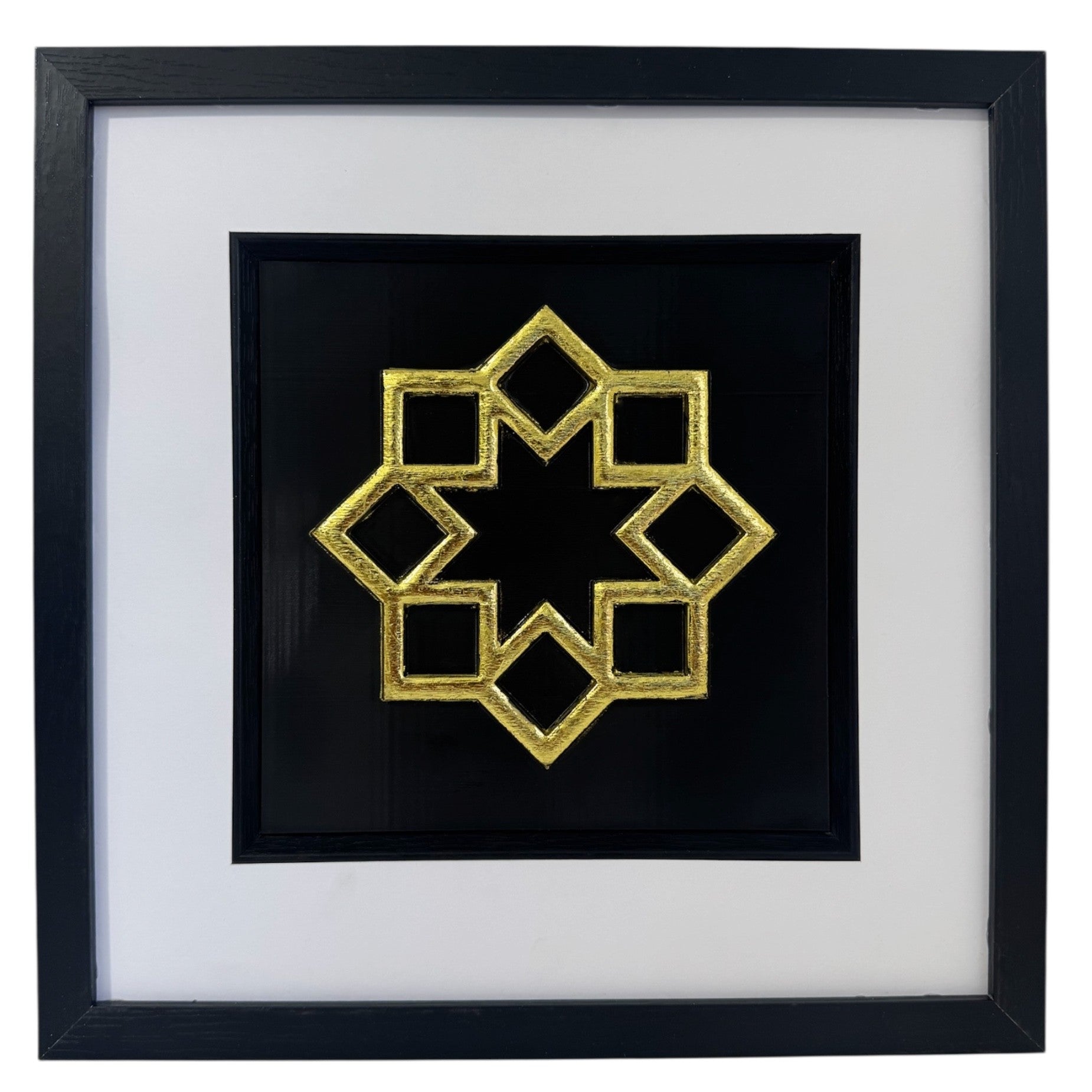 Gold framed Islamic geometric 8 point star relief on a black background with a wide white mount and black inner surround