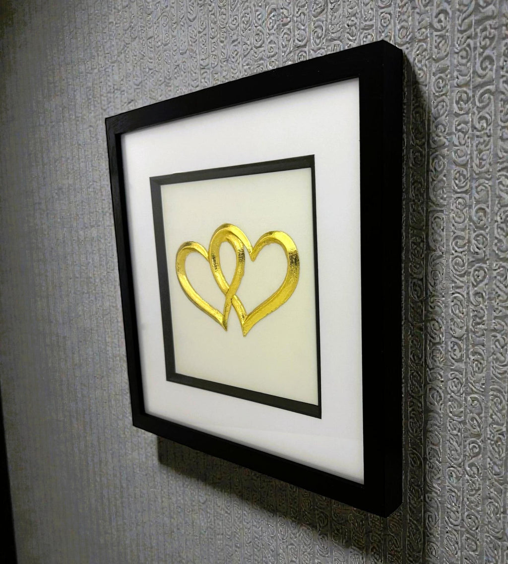 Angled wall-mounted joined hearts wall art framed in black with white mount