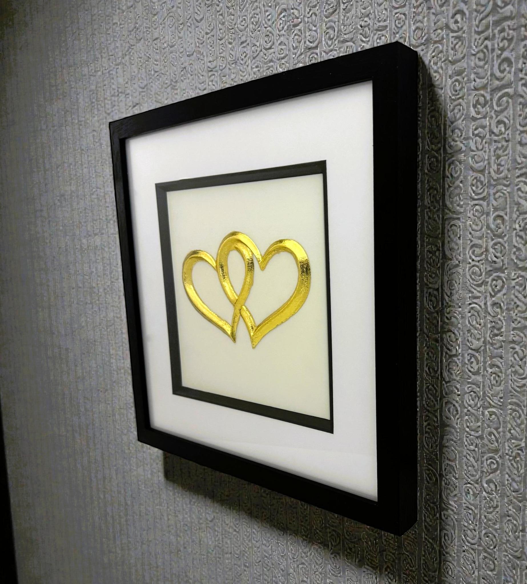 Angled wall-mounted joined hearts wall art framed in black with white mount