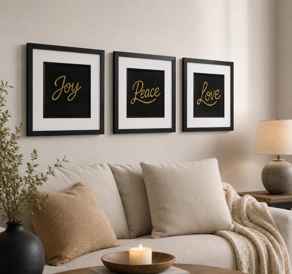 Angled lifestyle view of Gold Joy Peace Love framed wall art set above a sofa with lamp, cushions and wood tones
