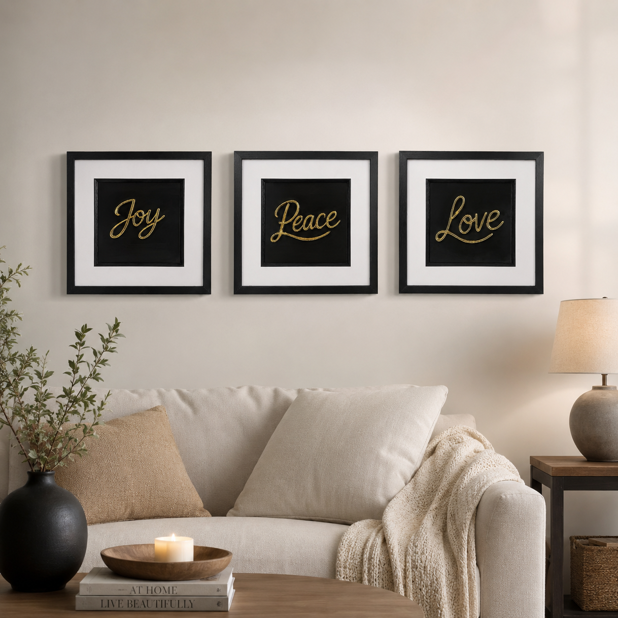 Gold Joy Peace Love 3D framed wall art trio styled above a cream sofa in a warm neutral living room