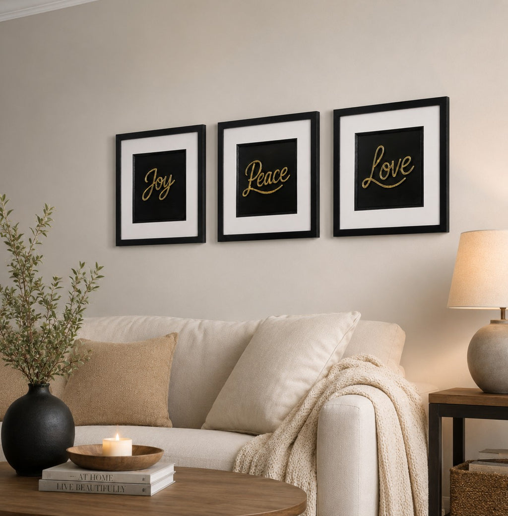 Gold Joy Peace Love 3D framed trio shown above a neutral sofa with soft lamp light, foliage and a wooden table
