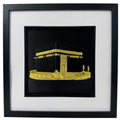 Gold Kaaba relief in a black box frame with wide white mount and black inner surround.