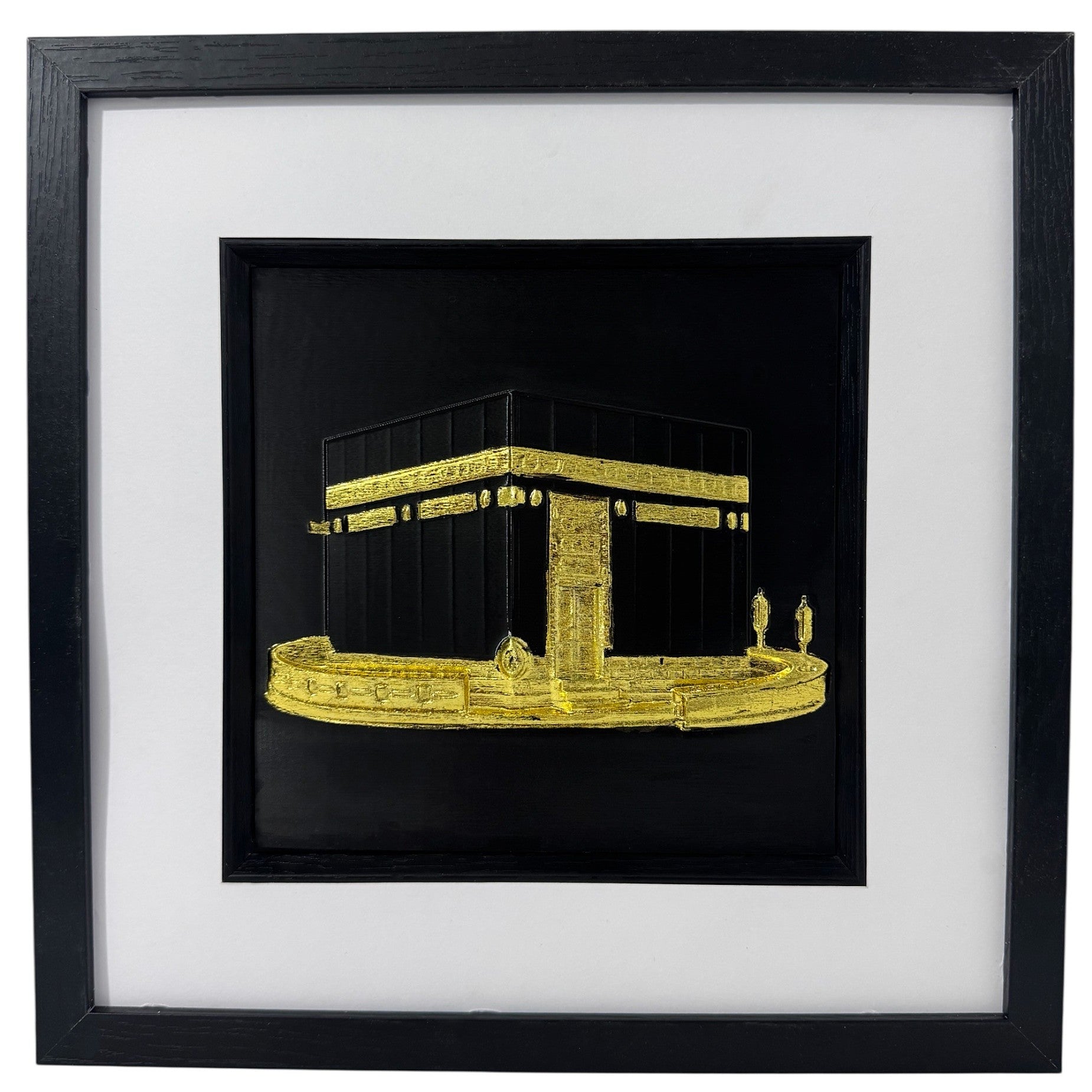 Gold Kaaba relief in a black box frame with wide white mount and black inner surround.