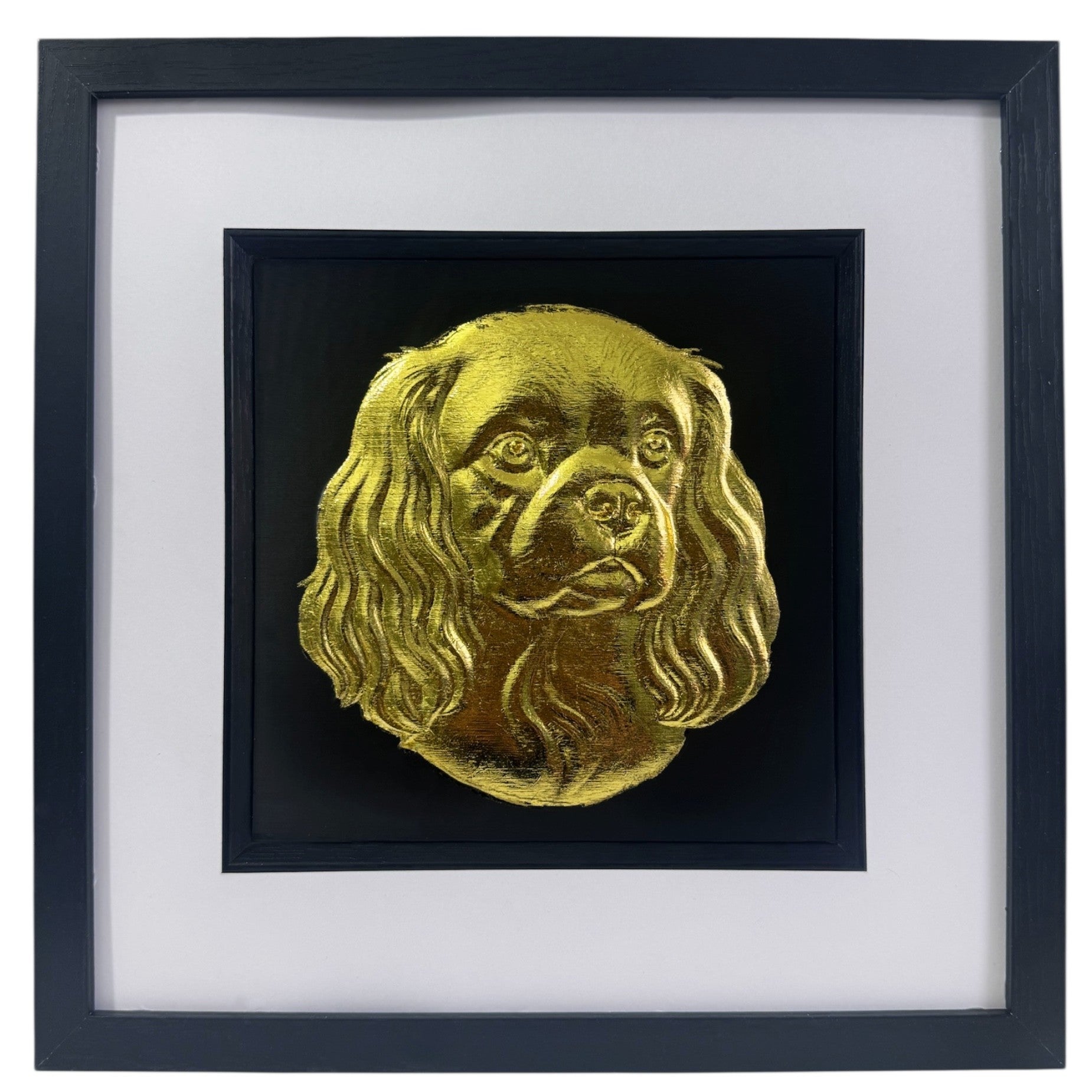 Cavalier King Charles Spaniel framed wall art showing a sculpted dog portrait with long ears in gold leaf, set on a black background with white mount and black wooden frame

