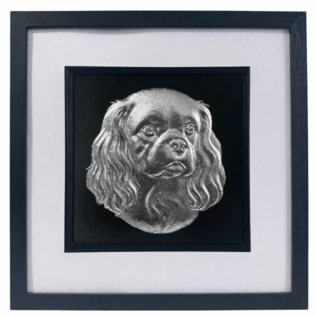 Cavalier King Charles Spaniel framed wall art showing a sculpted dog portrait with long ears in silver leaf, set on a black background with white mount and black wooden frame