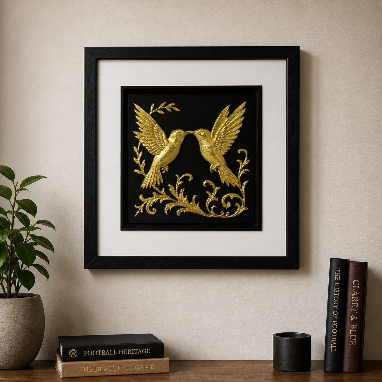 kissing hummingbird wall art gold leaf, on a neutral modern wall, with books