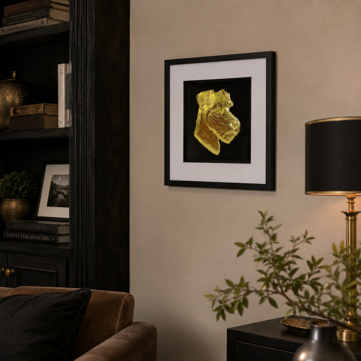 Angled lifestyle view of Lakeland Terrier gold leaf framed wall art hanging on a warm neutral wall in a luxury interior with dark wood, black and brass accents.