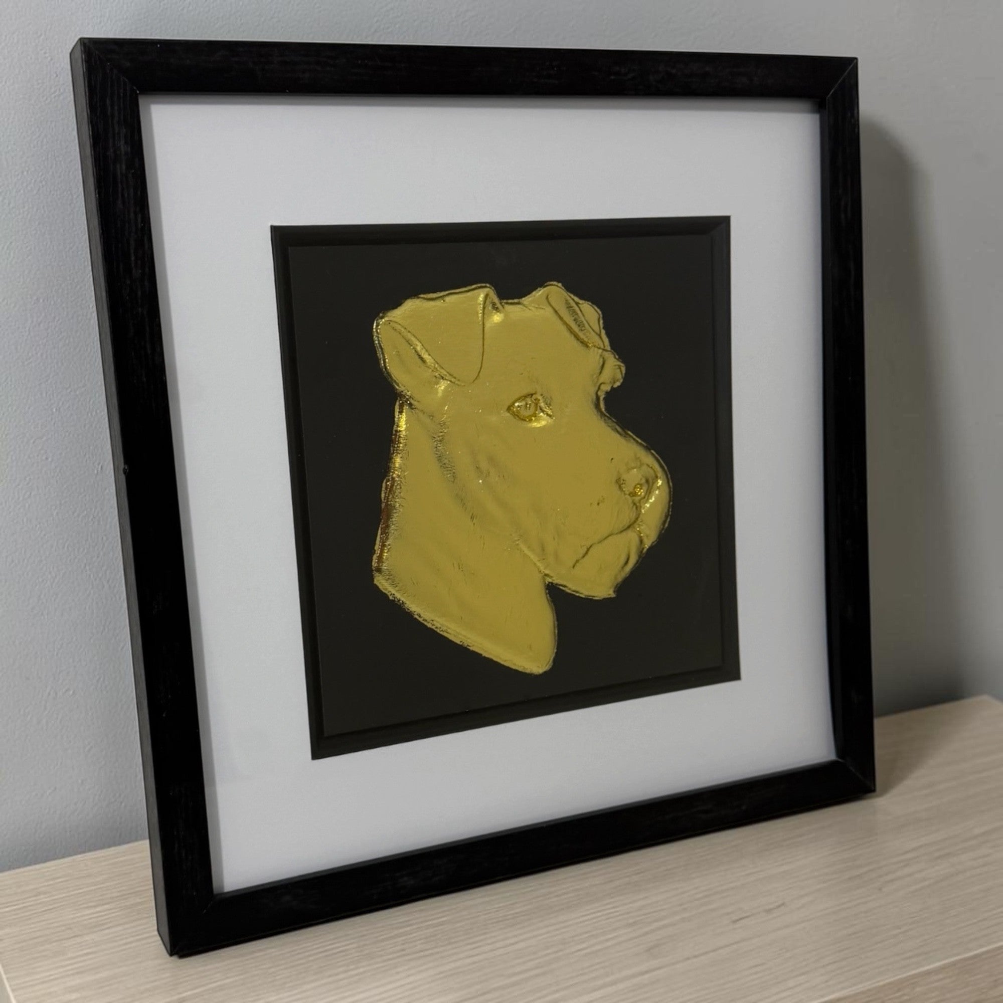 Lakeland Terrier framed wall art in silver leaf viewed at an angle, displayed in a black wooden frame with white mount